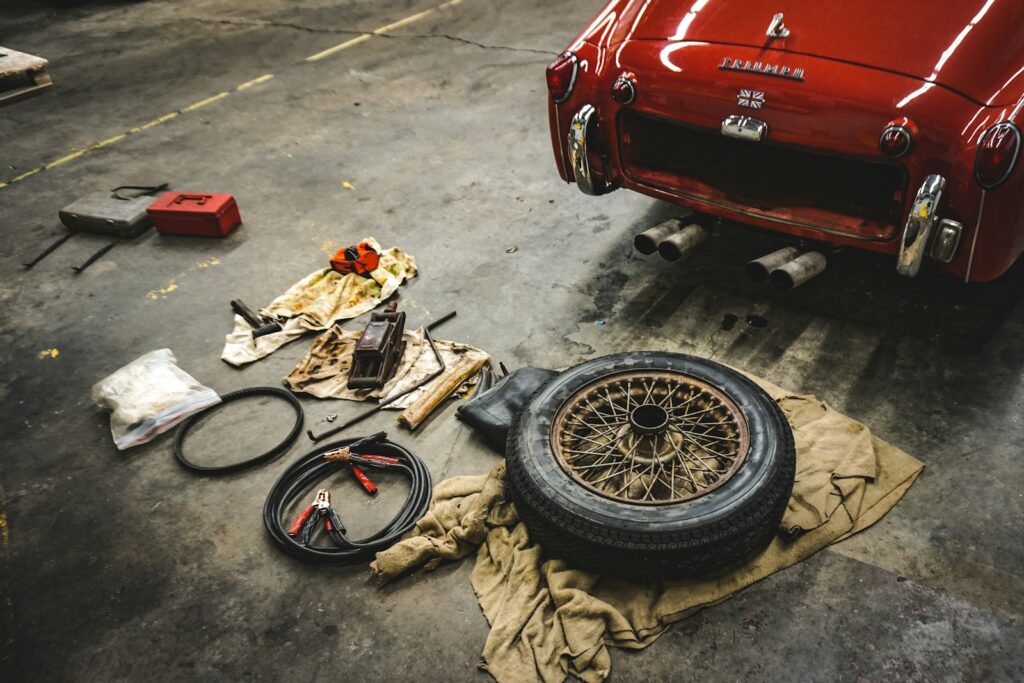 A red classic car parked inside a workshop garage